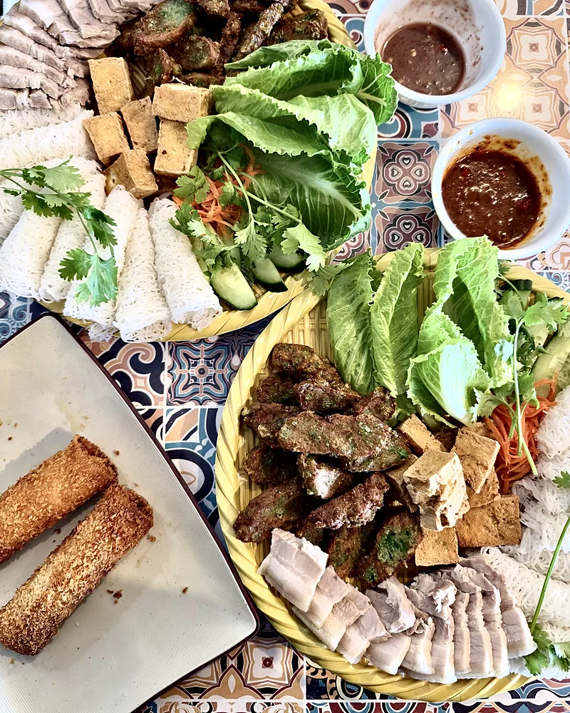 Share platter of grilled beef, fried tofu, sliced pork and woven rice vermicelli with lettuce, herbs and dipping sauces