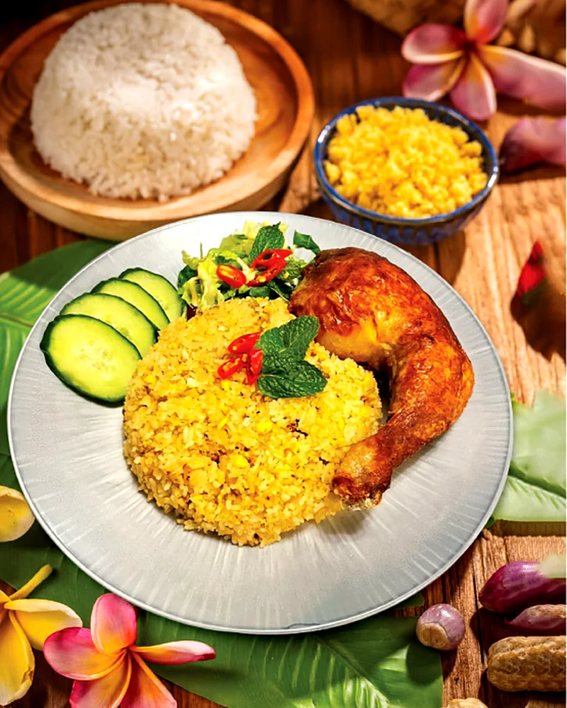 Crispy-skin chicken leg on yellow fried rice with cucumber slices