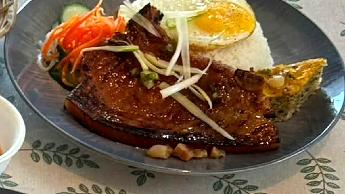 Broken rice with a grilled pork chop, fried egg, steamed egg meatloaf and pickled vegetables