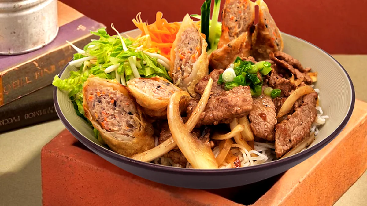 Rice vermicelli bowl topped with grilled pork, Vietnamese sausage and spring rolls